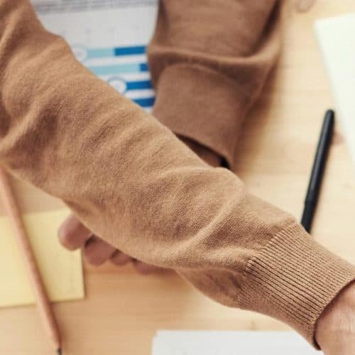 Top view of a diverse team fist bumping over a meeting table with paperwork and laptops, symbolizing teamwork.
