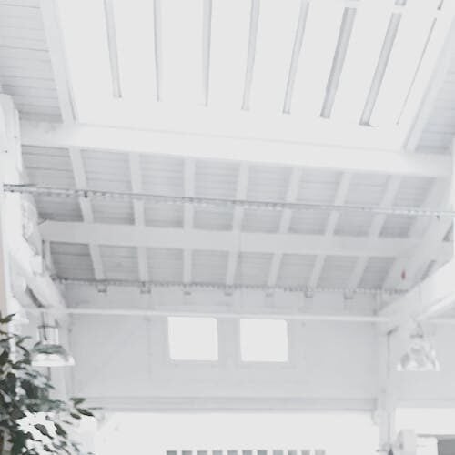 A bright, modern workspace featuring laptops, a camera, and a drawing tablet in an indoor office.